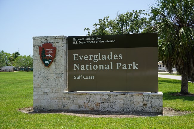 A large sign on a rock base that says "National Park Service, US Department of the Interior, Everglades National Park, Gulf Coast."
