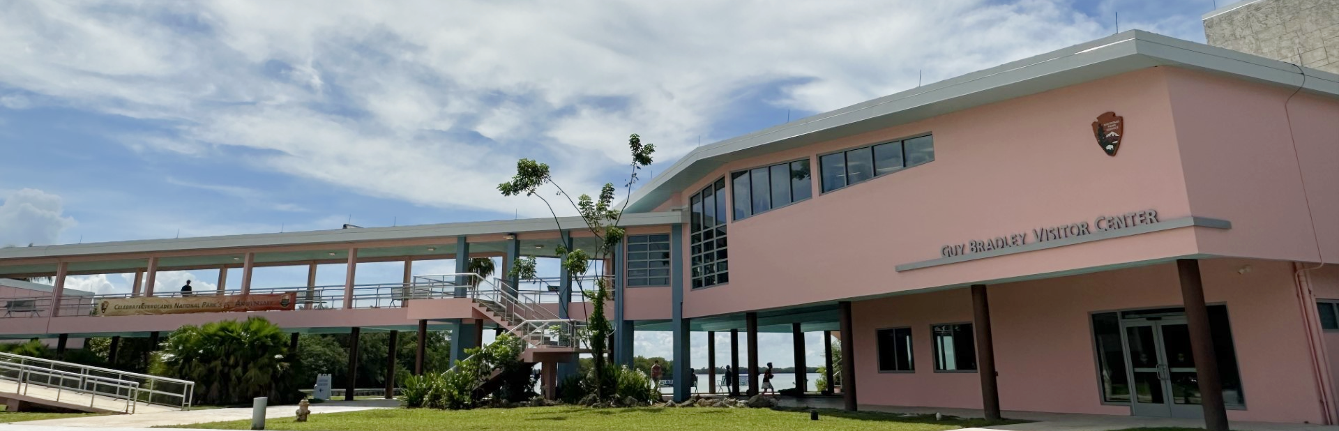 A two-story pink building with a breezeway connecting it to a gray building.