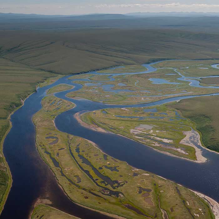A meandering river flows along a vast grassy landscape.