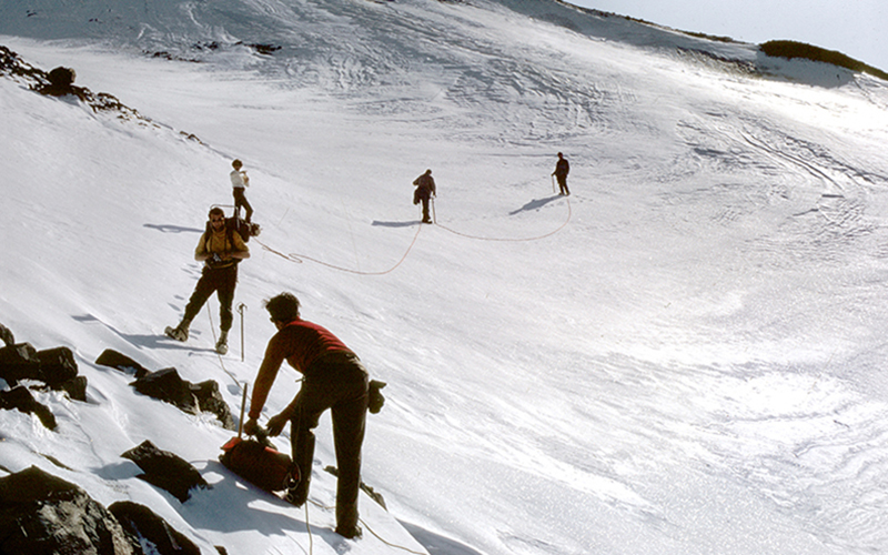 Mountaineers lined up and holding a rope in the Harding Icefield during an expedition in 1968.