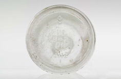 Bottom of aged clear glass bottle with imprinted markings.