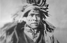 Portrait of a Native American man wearing a headdress.