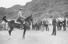 Man in uniform rides horse in front of crowd.