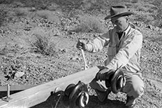 Man wearing hat using a wrench on power pole laying on ground. 