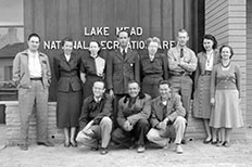 Eleven people pose for a photo in front of Lake Mead National Recreation Area sign. 

