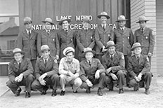 Thirteen uniformed NPS personnel pose for a photo in front of the Lake Mead National Recreation Area sign.