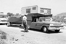 Uniformed officer approaching a camper with a boat attached.