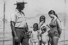 Uniformed Park Ranger and Lifeguard talking to young swimmers at the beach.