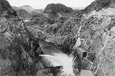 Looking down deep canyon with water at bottom, water is spraying into canyon from concrete structure at lower left.