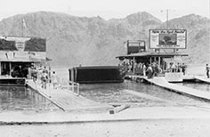 Small crowd of people on docks with small buildings at the end.