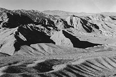 Mountains with pointed ridges at the tops and small ridges of desert landscape across the bottom.