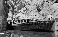 Boat on lake and between mountains with people on it.