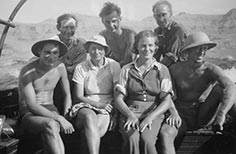 Seven people pose for a photo while sitting on a boat.