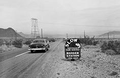 Car driving on road next to National Park Service sign.