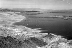 Large body of water with boats scattered across and rock formations throughout, showcasing water line markings and creating a shoreline.