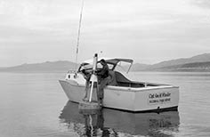 Two men on a boat on the lake fixing a floating beacon.