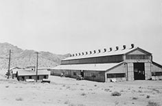 Large building with a car and some smaller buildings next to it.