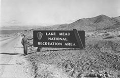 Man in uniform stands next to Lake Mead sign.