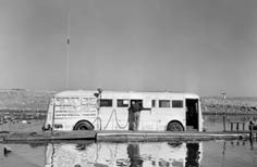 Man stands on a dock at window of bus food stand.