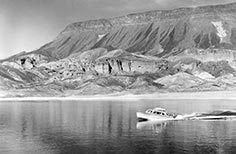 Single boat on a lake with mountains in background.