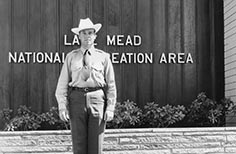 Man in uniform poses in front of National Park Service building.