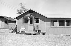 Building that has a porch with two chairs on it.