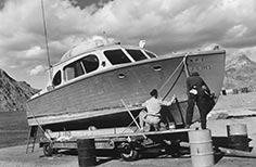 Two men scrub hull of boat that is on a boat trailer.