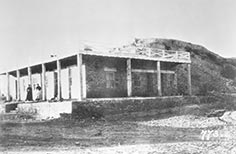 Two people stand on porch of building with many columns.