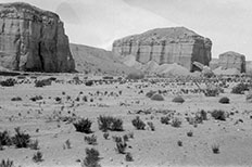 Three spaced out rectangle shaped mountains with desert landscape along the bottom.

