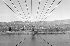 Ferry suspended in the air above a river with several cables.