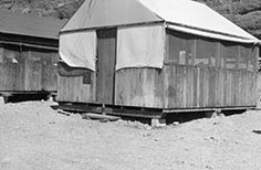 Angled view of small cabin with screen covered windows and a canvas roof.