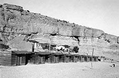 Small cabins lined up in front of a cliff.
