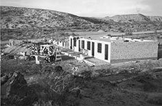 Single story brick building under construction in desert surroundings.