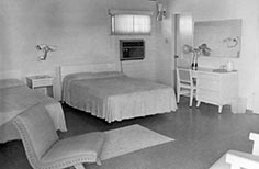 Interior of room with two beds, two chairs, and a desk with a chair.