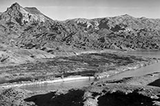 Narrow section of river in lower foreground, mountain range behind.