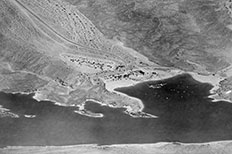 Aerial view of river with marina in large cove, roads and developed area above.