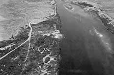 Aerial view of river at right, dense foliage at lower left, desert upper left.