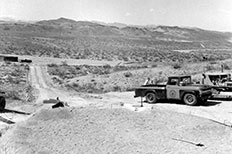 Elevated view of construction of round sand filled foundation, pickup truck at center right.