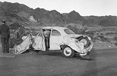 Park Ranger stands next to a wrecked car.