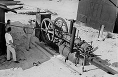 Three men stand next to machinery.