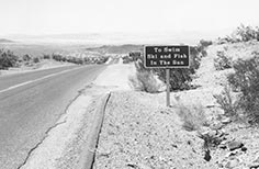 Sign next to road that reads To Swim Ski and Fish in the Sun.