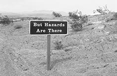 Sign next to road that reads But Hazards are There.