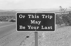 Sign next to road that reads Or This Trip Could Be Your Last.