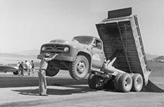 Man stands next to dump truck.