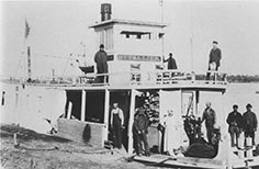 Double decker steam boat with many people on it.