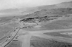 Aerial view of small city surrounded by desert and lake at upper left.