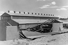 Metal building with roof blown off exposing the objects inside. 