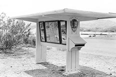 Covered wooden post with a National Park Service arrowhead and framed exhibit information.

