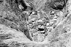 Small stone dam in wash between steep rocks.