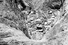 Small stone dam in wash between steep rocks.